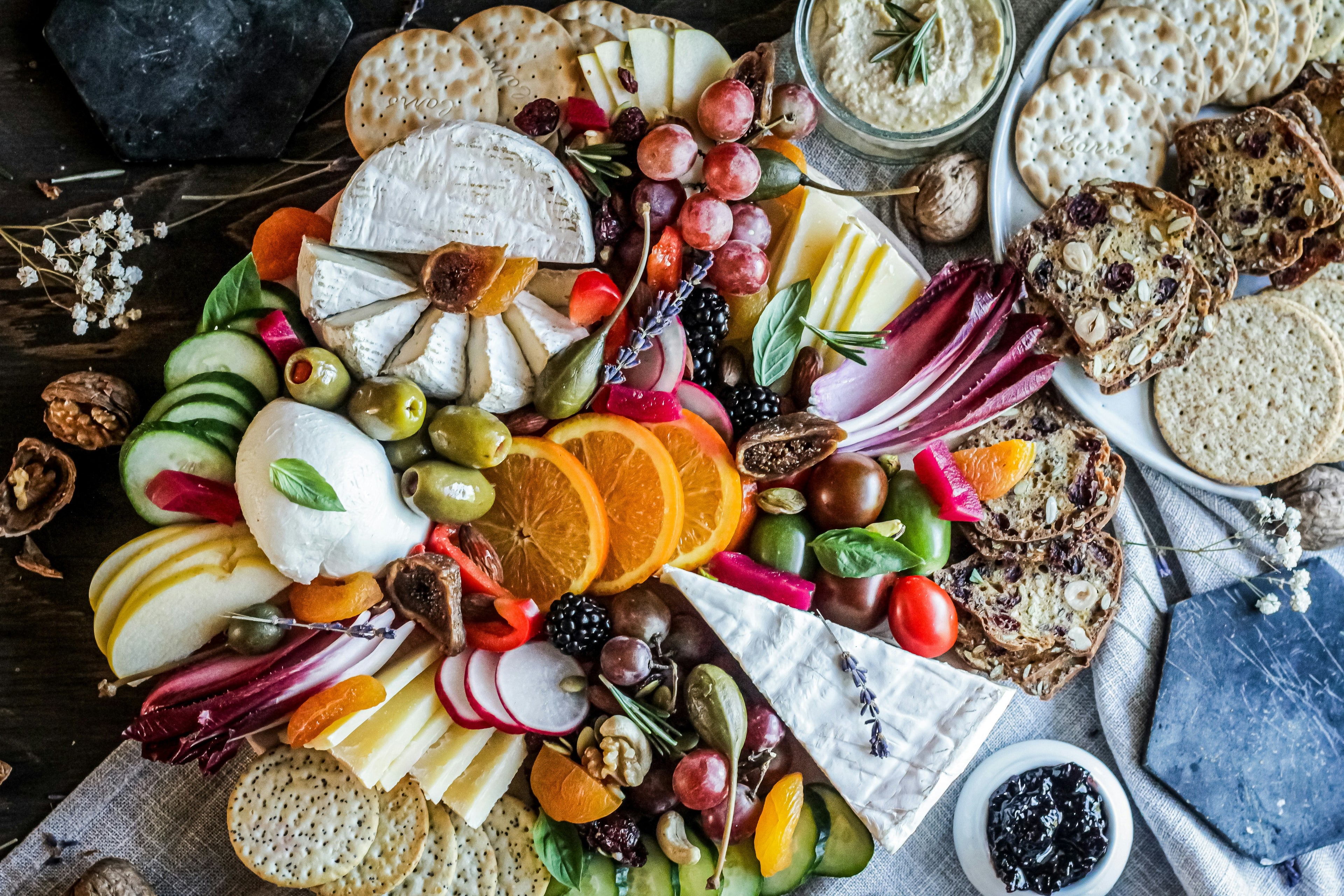 Designer placeholder: artful charcuterie and catering spread with cheese, fruit, bread, and vibrant seasonal garnishes.